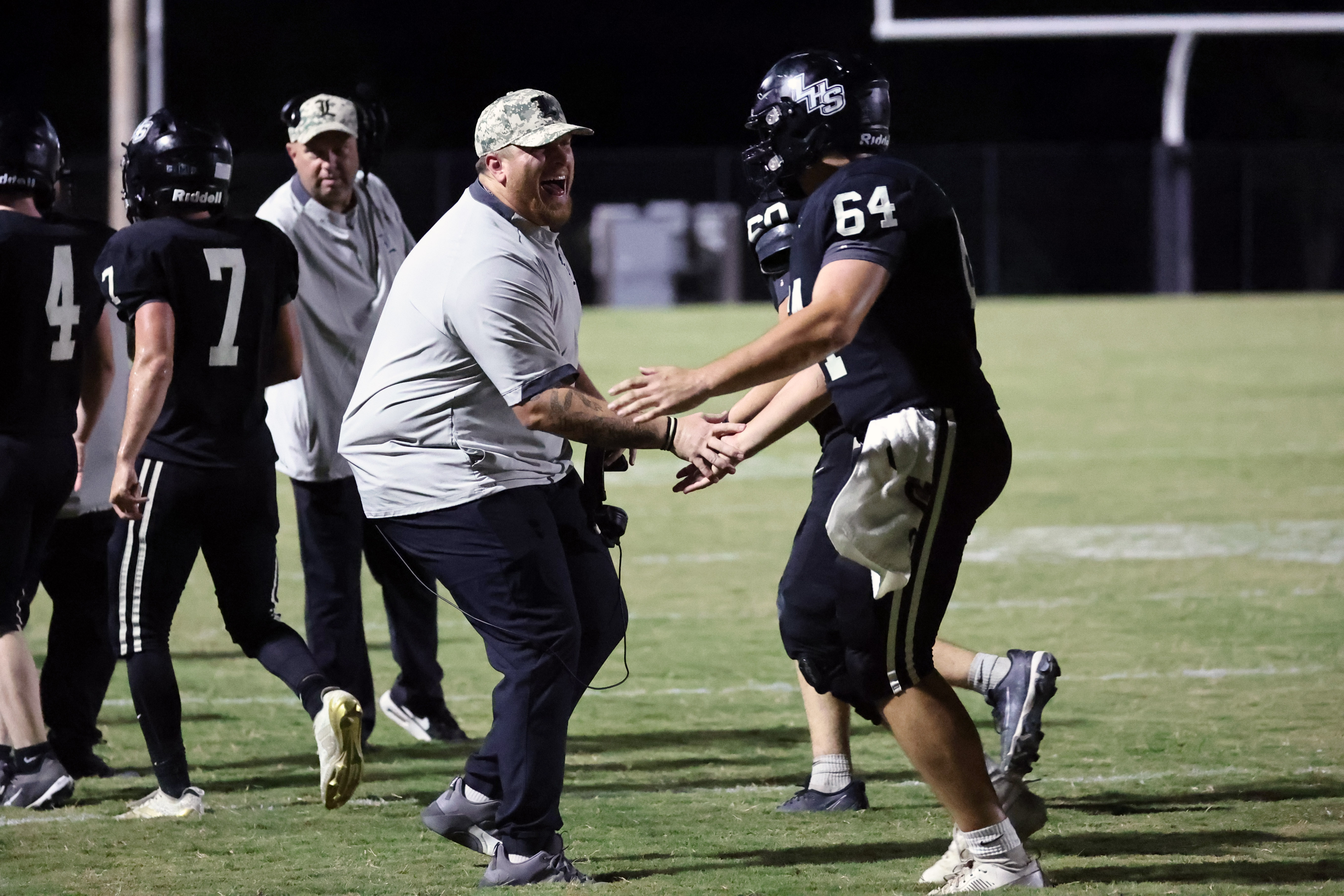 Mustangs assistant coaches Daniel Smith and Josh Brown congratulate players as they come off the field after scoring a touchdown.